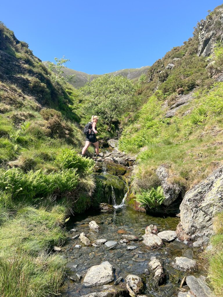 A woman walking across the top of a small waterfall