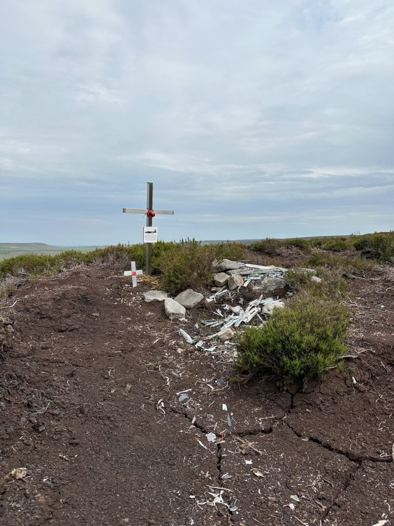 The remains of the Wellington R1011, a collection of old metal pieces and a memorial cross