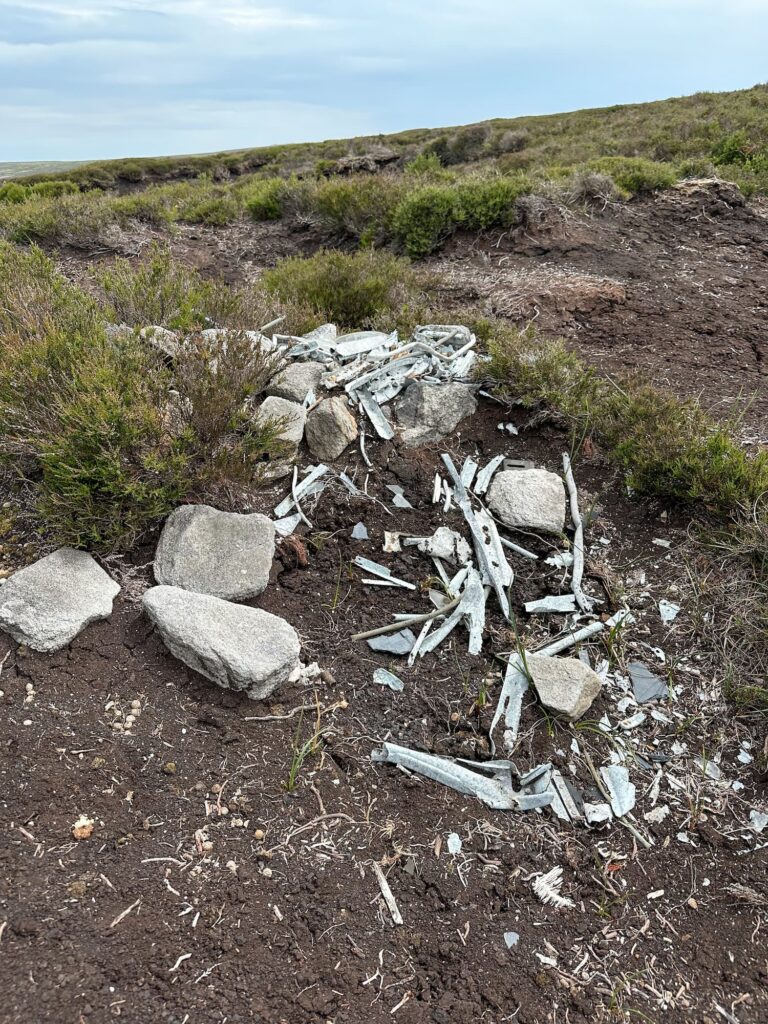 The remains of the Wellington R1011, a collection of old metal pieces and a memorial cross