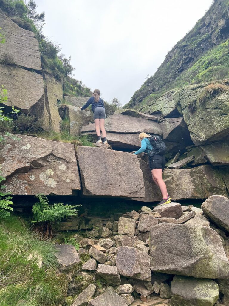 A woman scrambling up some rock