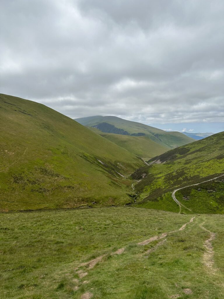 A view of the Uldale Fells, rolling green hills with a grey cloudy sky