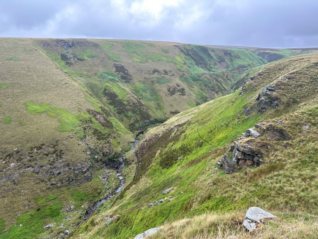 A rocky valley with steep sides, as seen from the top of one of the sides