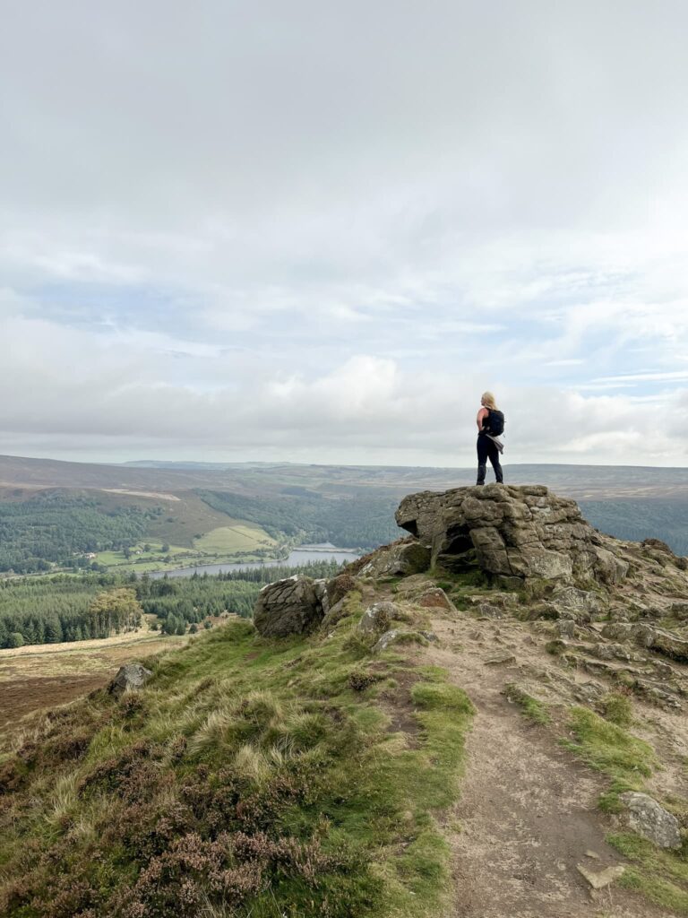 A woman stood on a rock at the top of Win Hill