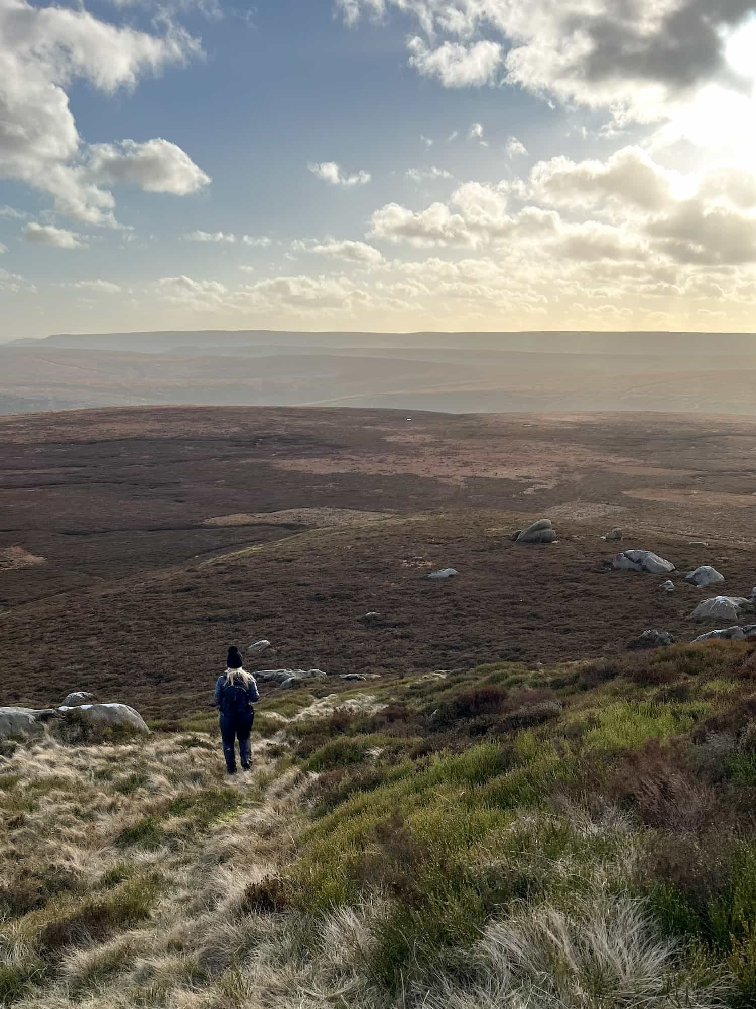 A lone figure walking downhill on some remote moors