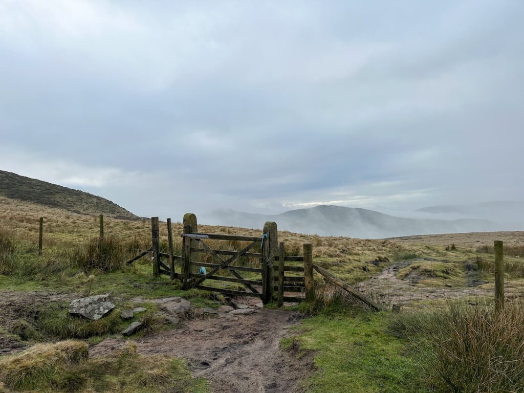 A wooden gate with a view of a misty landscape beyond