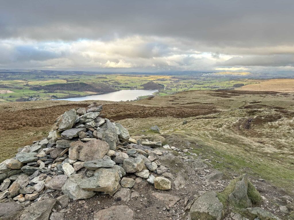 A small stone cairn on top of a hill overlooking Ullswater