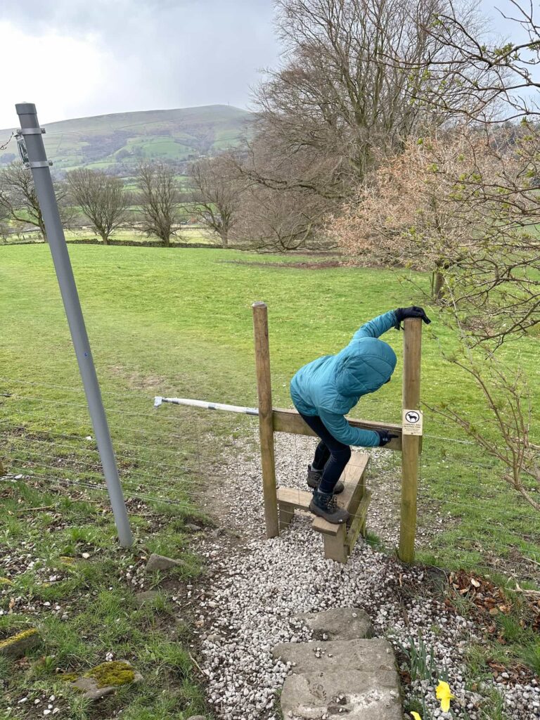 A young girl of about 12 climbing over a stile