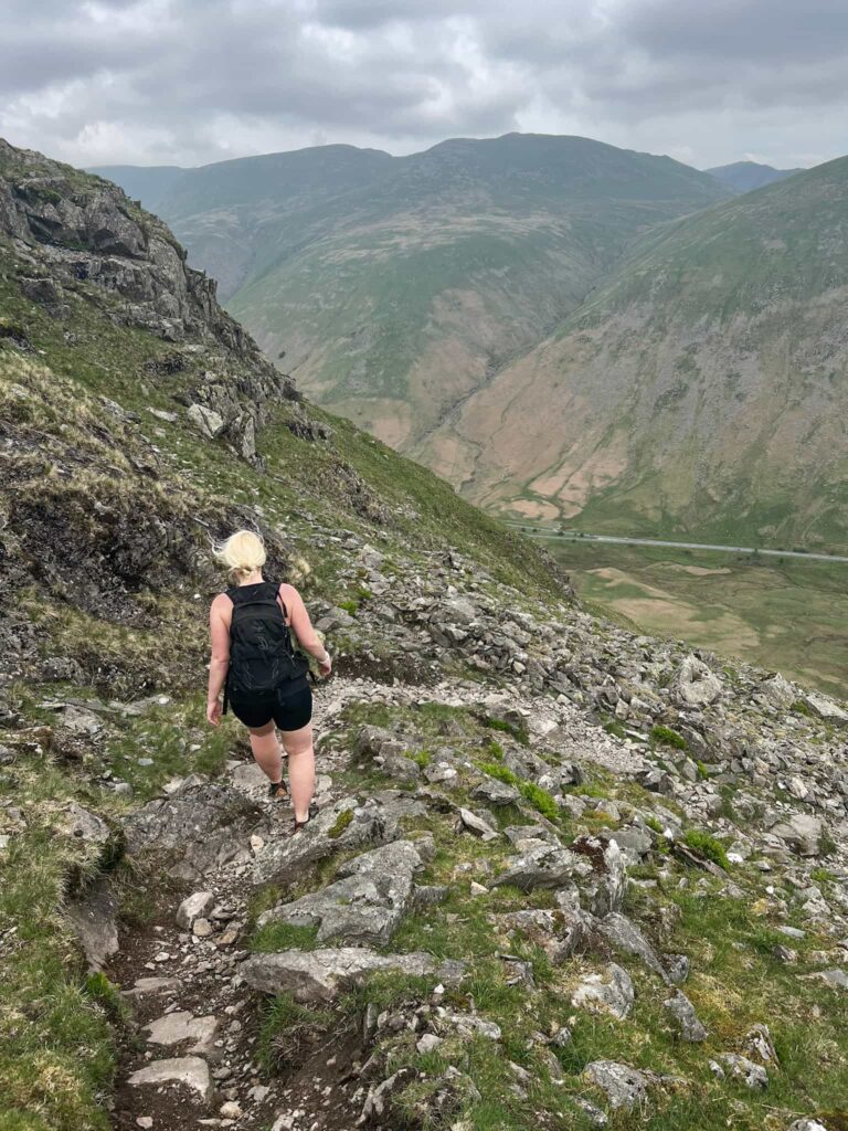 A blonde haired woman descending a rocky path