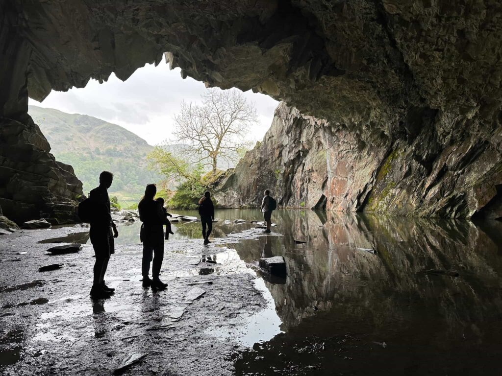 A queue of people sillhouetted against a cave entrance