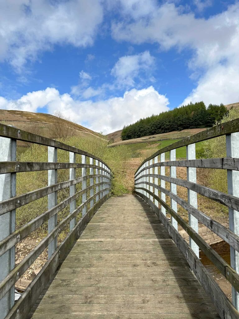 A path running over a wooden bridge with moorland beyond