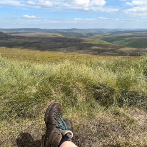 Boots with a view - a pair of hiking boots in the foreground, with expansive moorland as the view