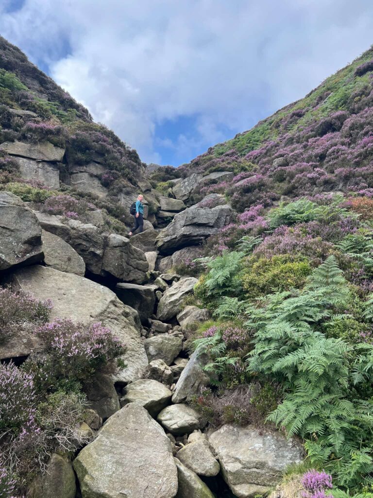 A woman climbing up some rocks in Jaggers Clough