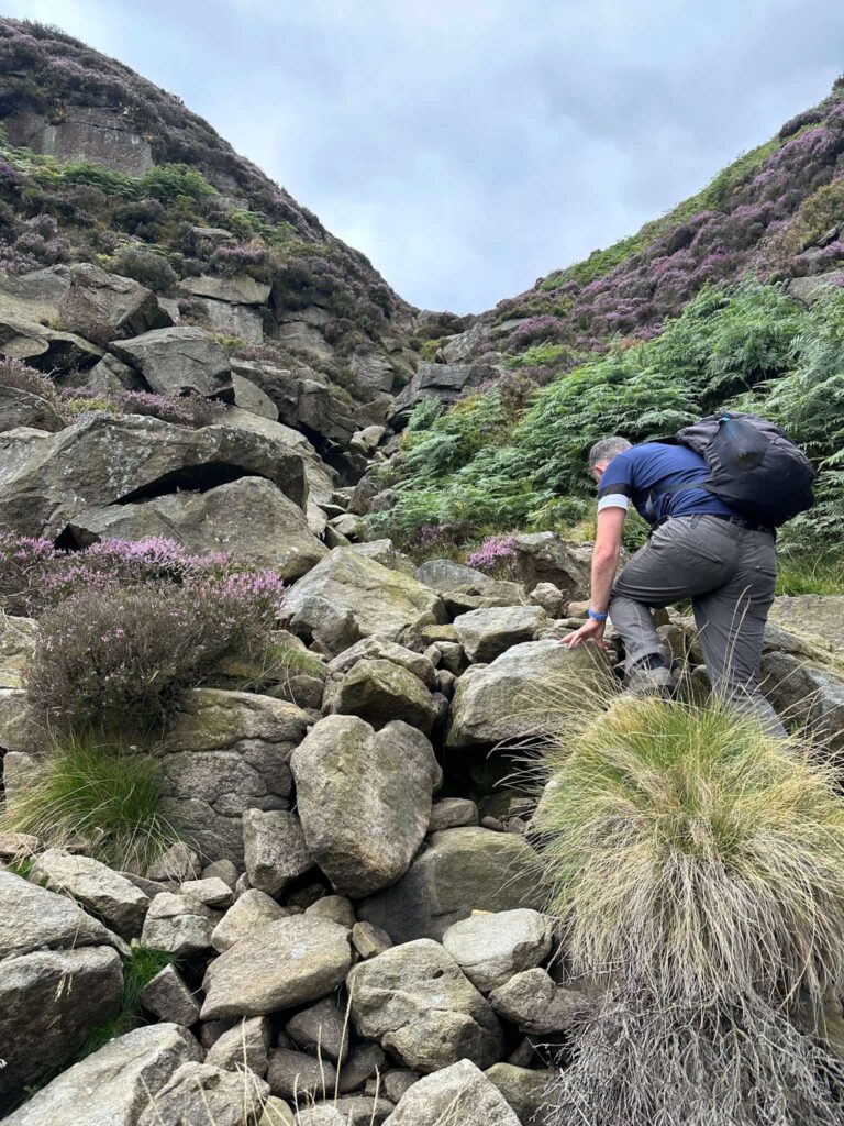 A man climbing up some rocks in Jaggers Clough