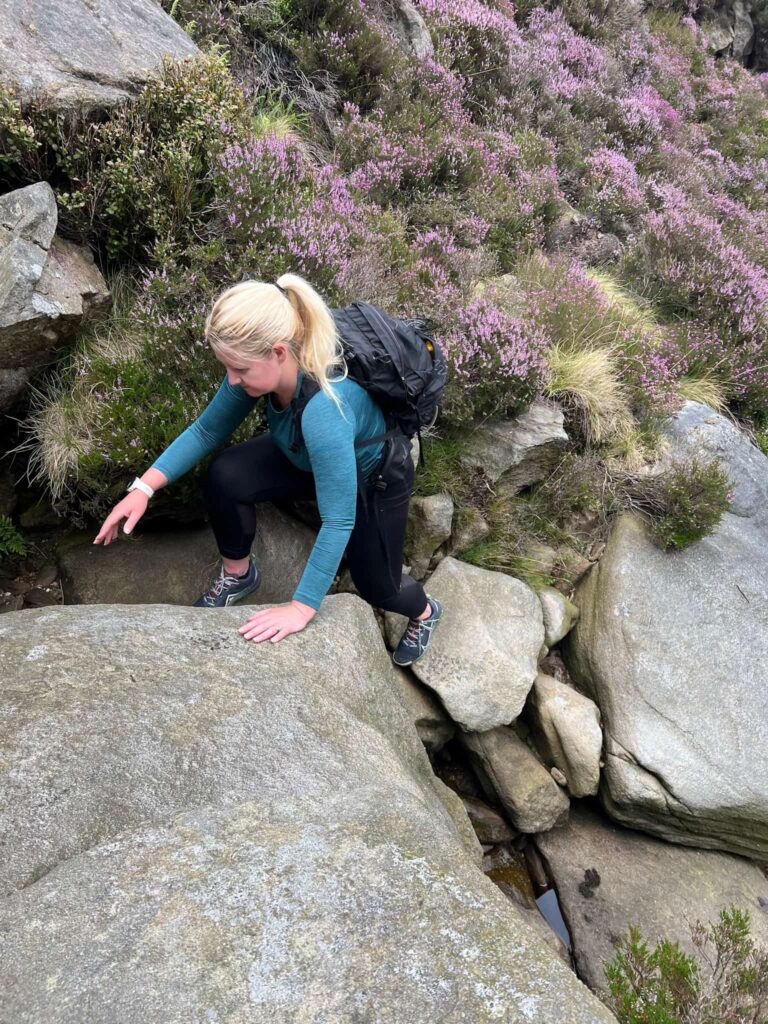 A woman climbing up some rocks in Jaggers Clough