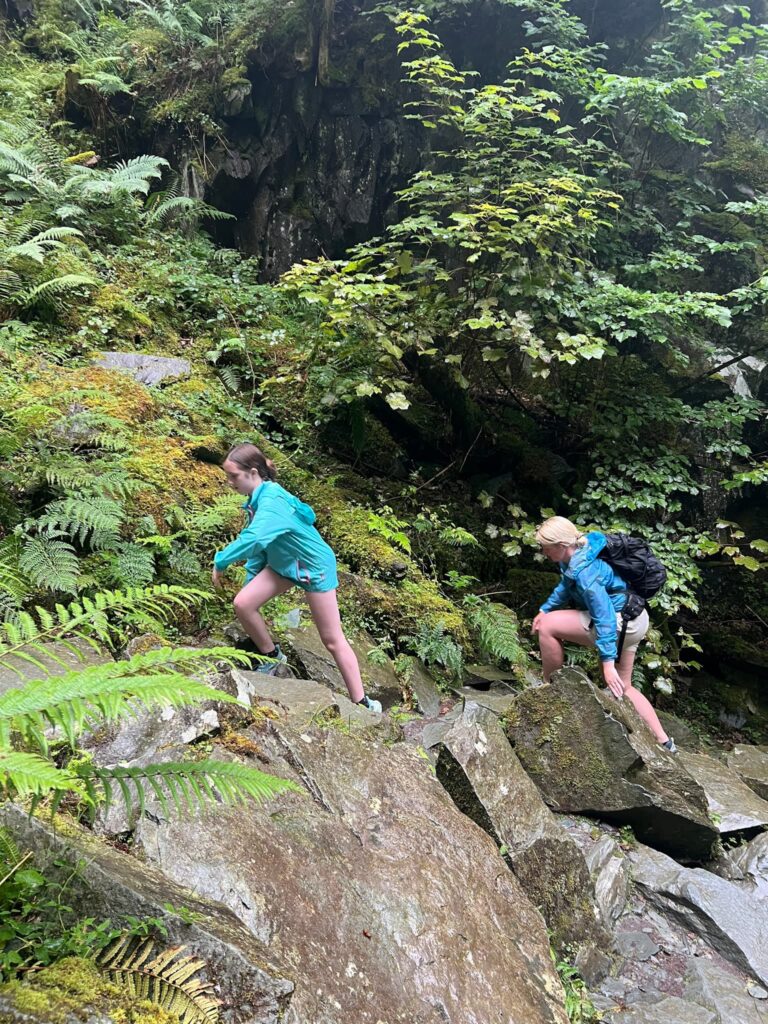 Two people in blue coats climbing over some rocks