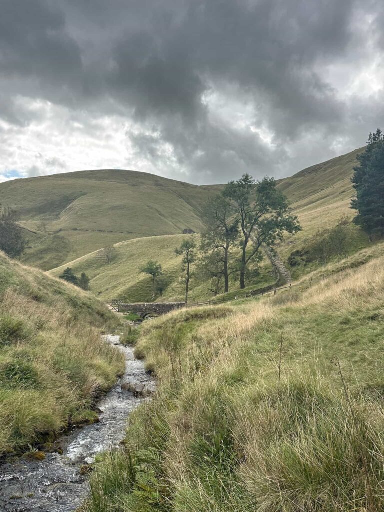 A view of the River Noe running under an old packhorse bridge at the foot of the path known as Jacob's Ladder