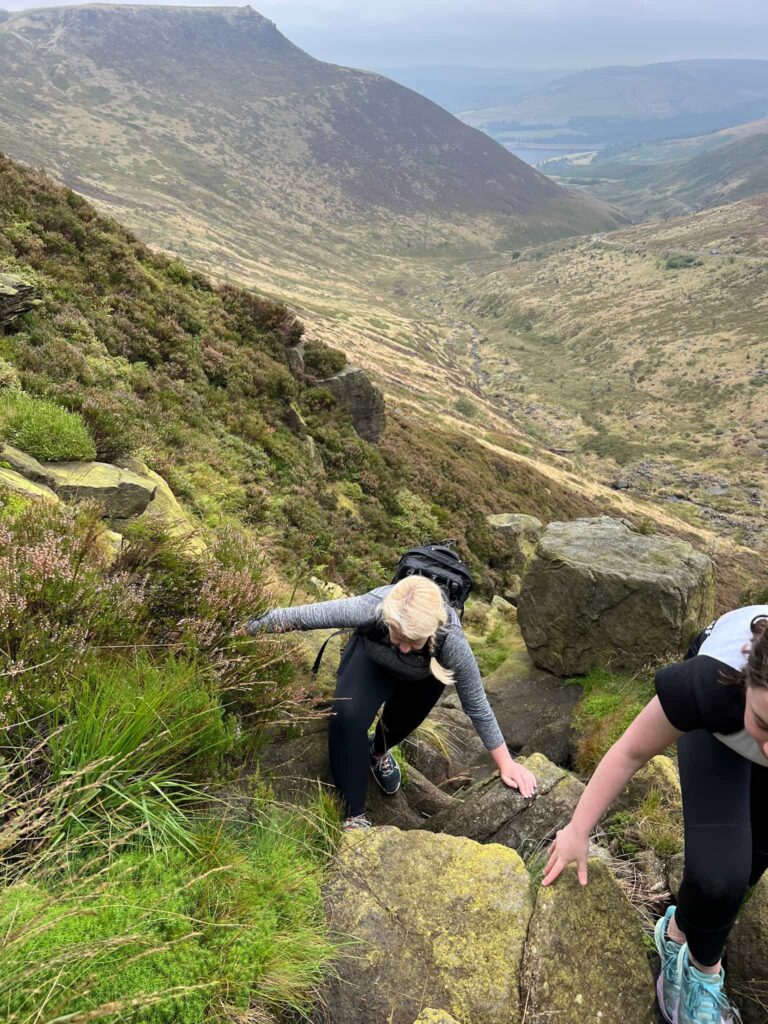 A woman scrambling up a rocky hillside