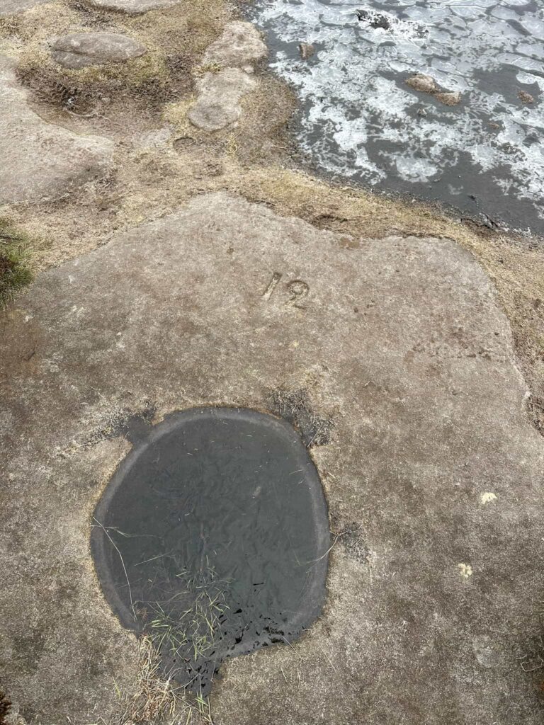 A stone with a dip for water collection and the number 12 