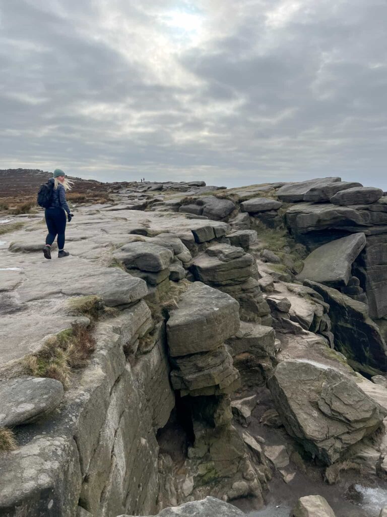 A woman walking on a gritstone edge