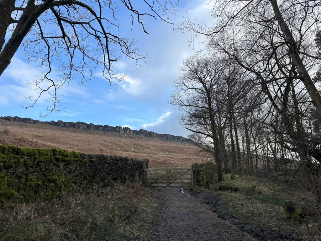 A wooden gate with Stanage Edge beyond