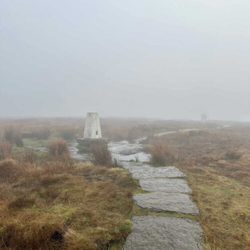 A stone slabbed path on the moors, leading to a white trig point