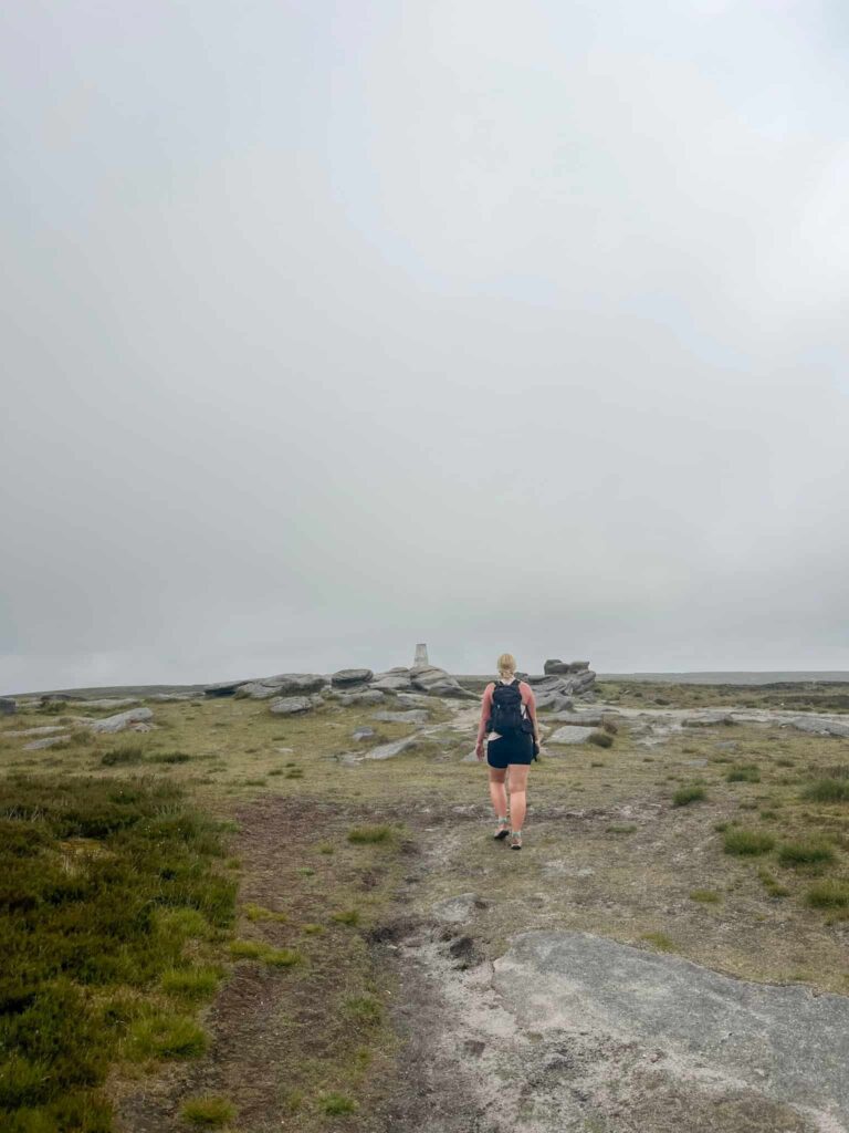 A woman walking to a trig point