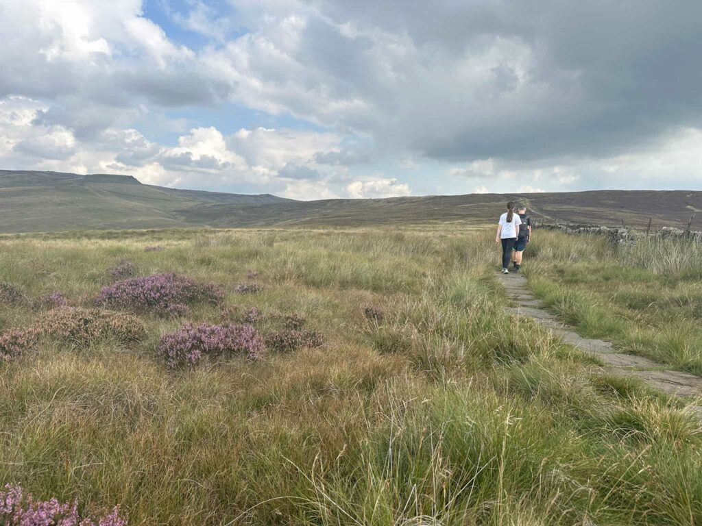 A man and his daughter walking on the stone slabs on the moors