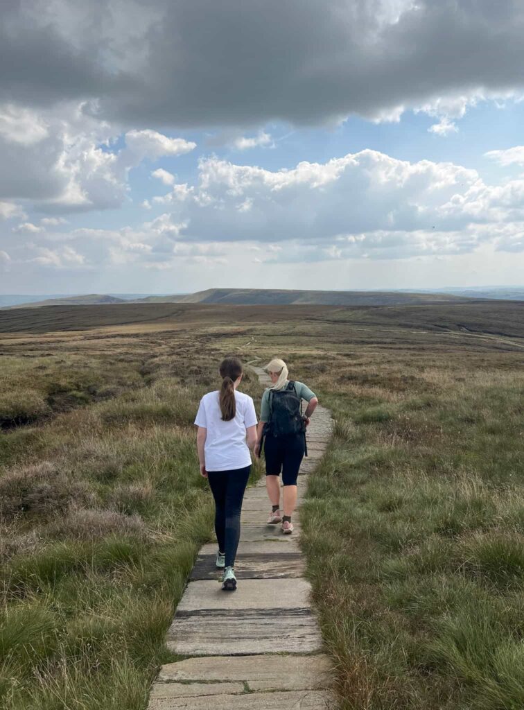 A woman and her daughter walking on stone slabs on the moors