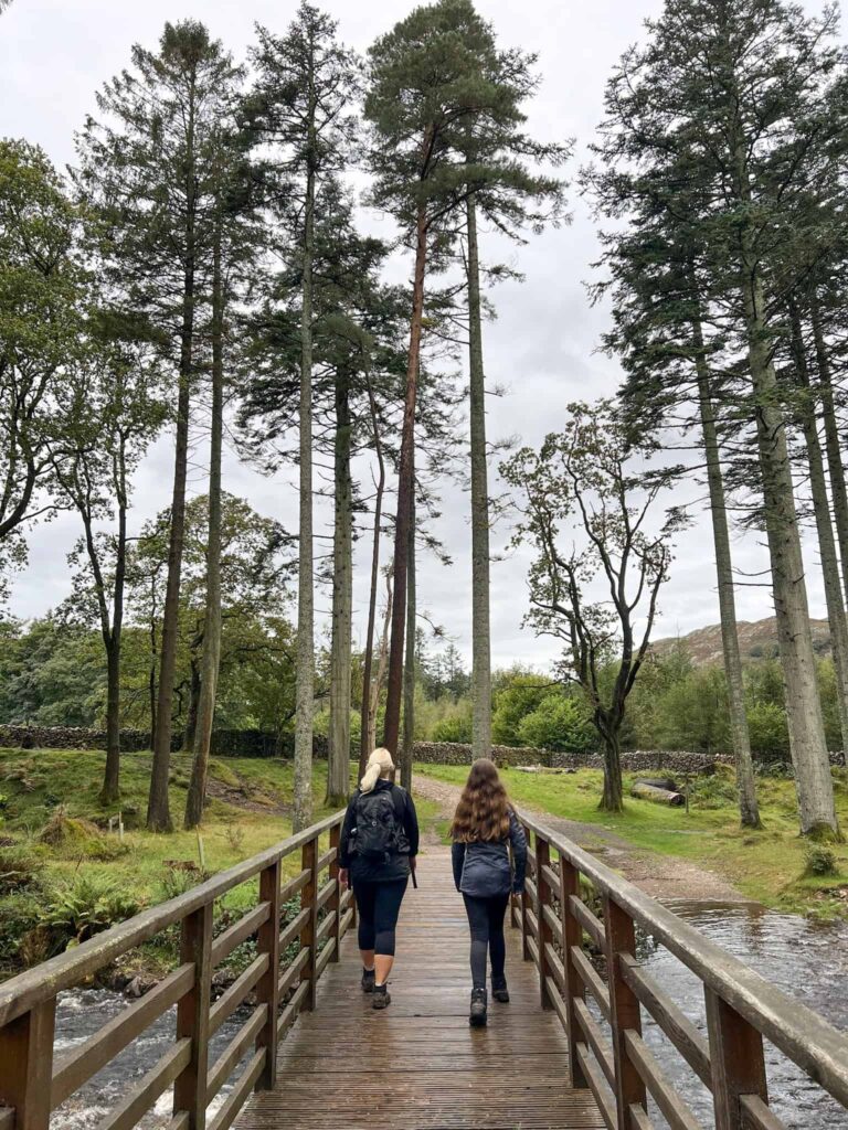 A woman and her daughter walking over a wooden bridge