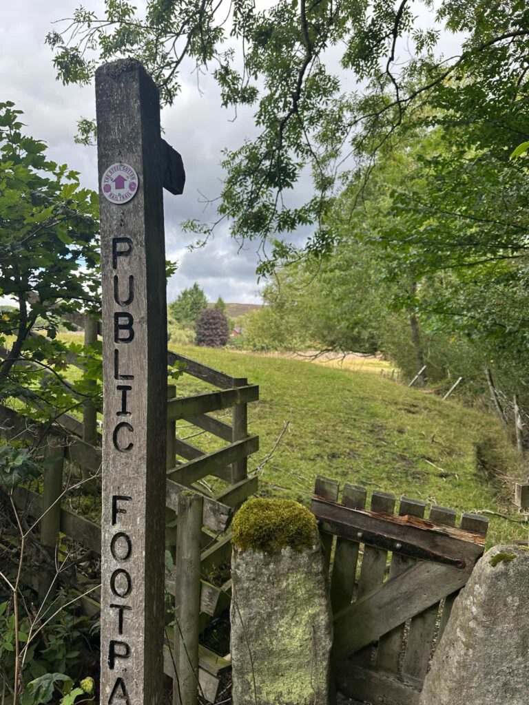 A wooden sign post with a Steel Cotton Rail Trail marker