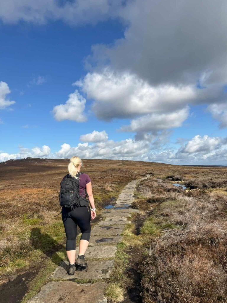 A woman walking on a stone flagged path on the moors