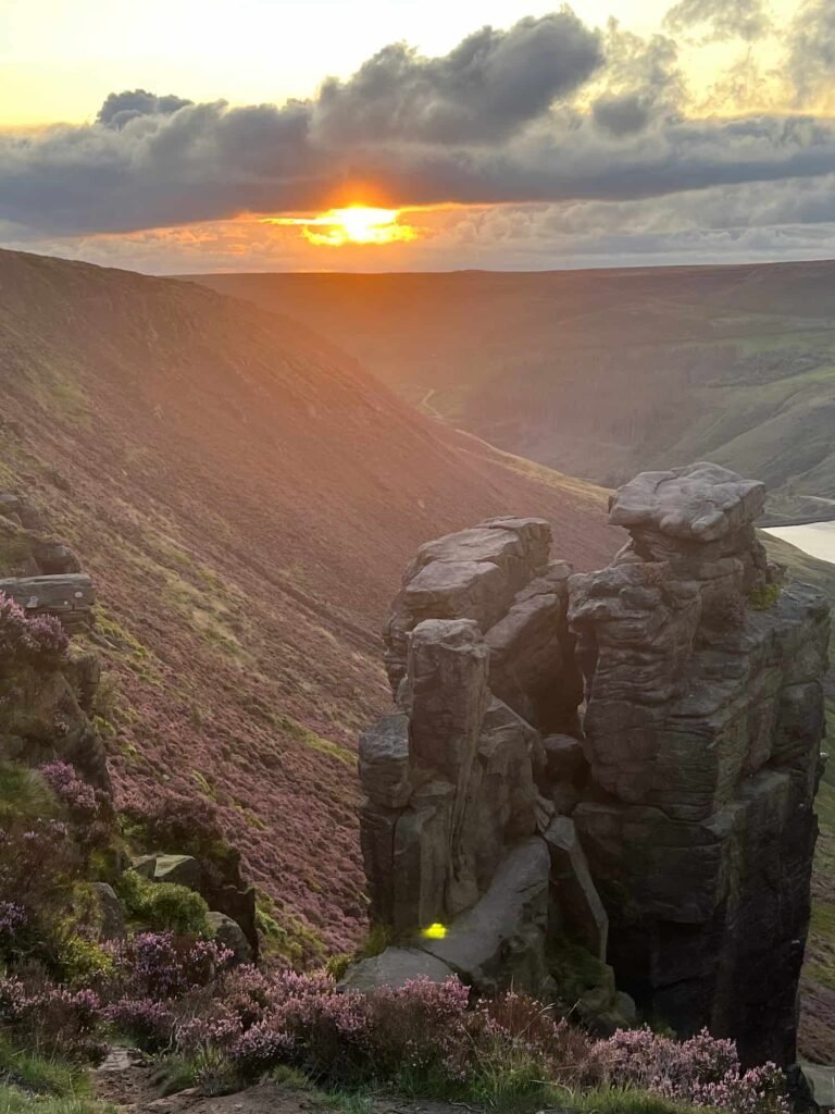 The Trinnacle rock formation with a view of Dove Stone Reservoir at sunset