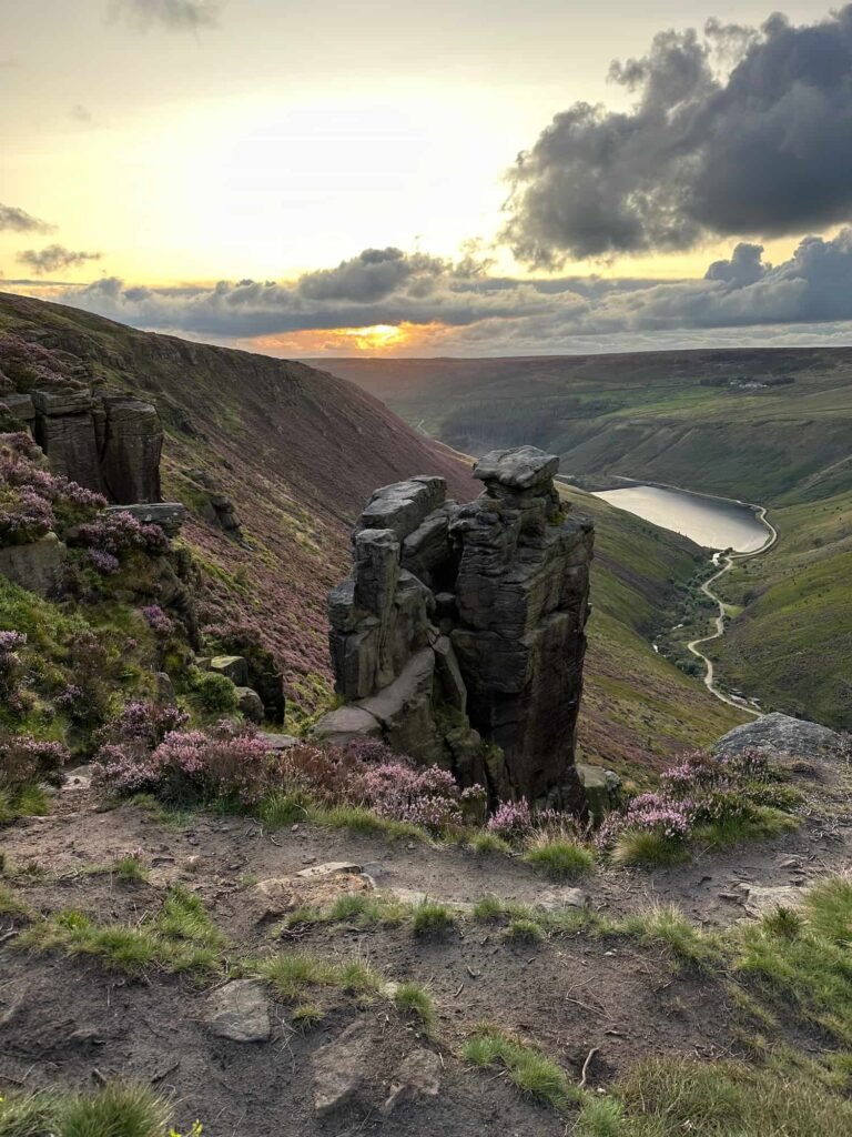 The Trinnacle rock formation with a view of Dove Stone Reservoir at sunset