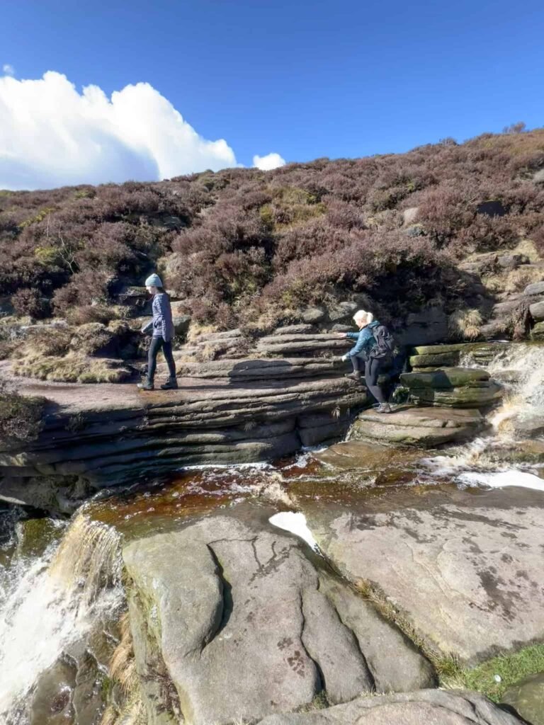 A woman and her daughter crossing a waterfall