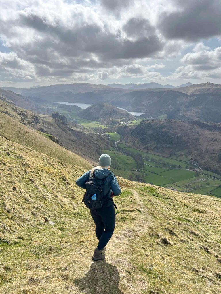 A woman walking down a steep hill in the Lake District