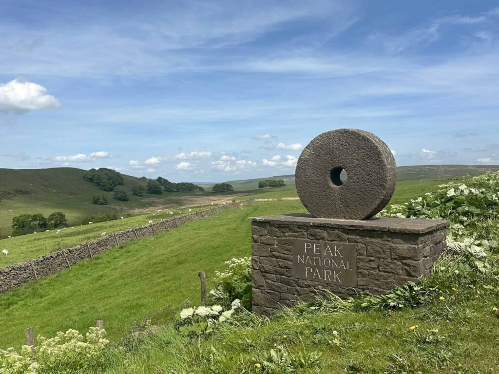 A Peak District boundary marker of an old circular millstone on a plinth