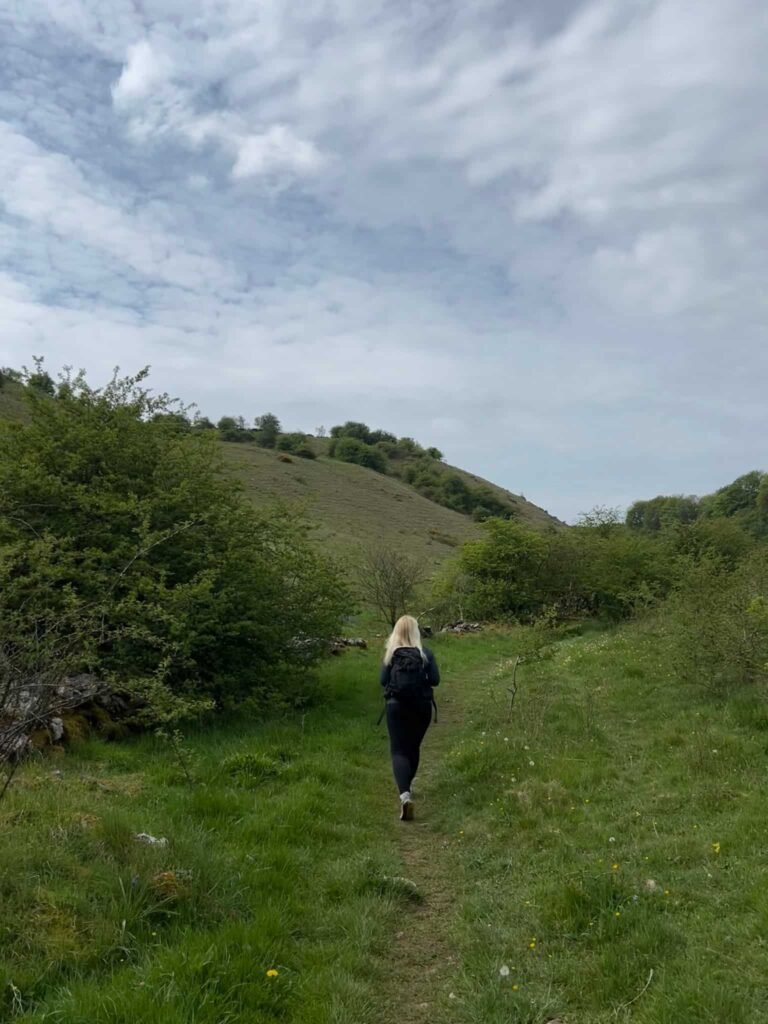 A woman walking in a grassy valley