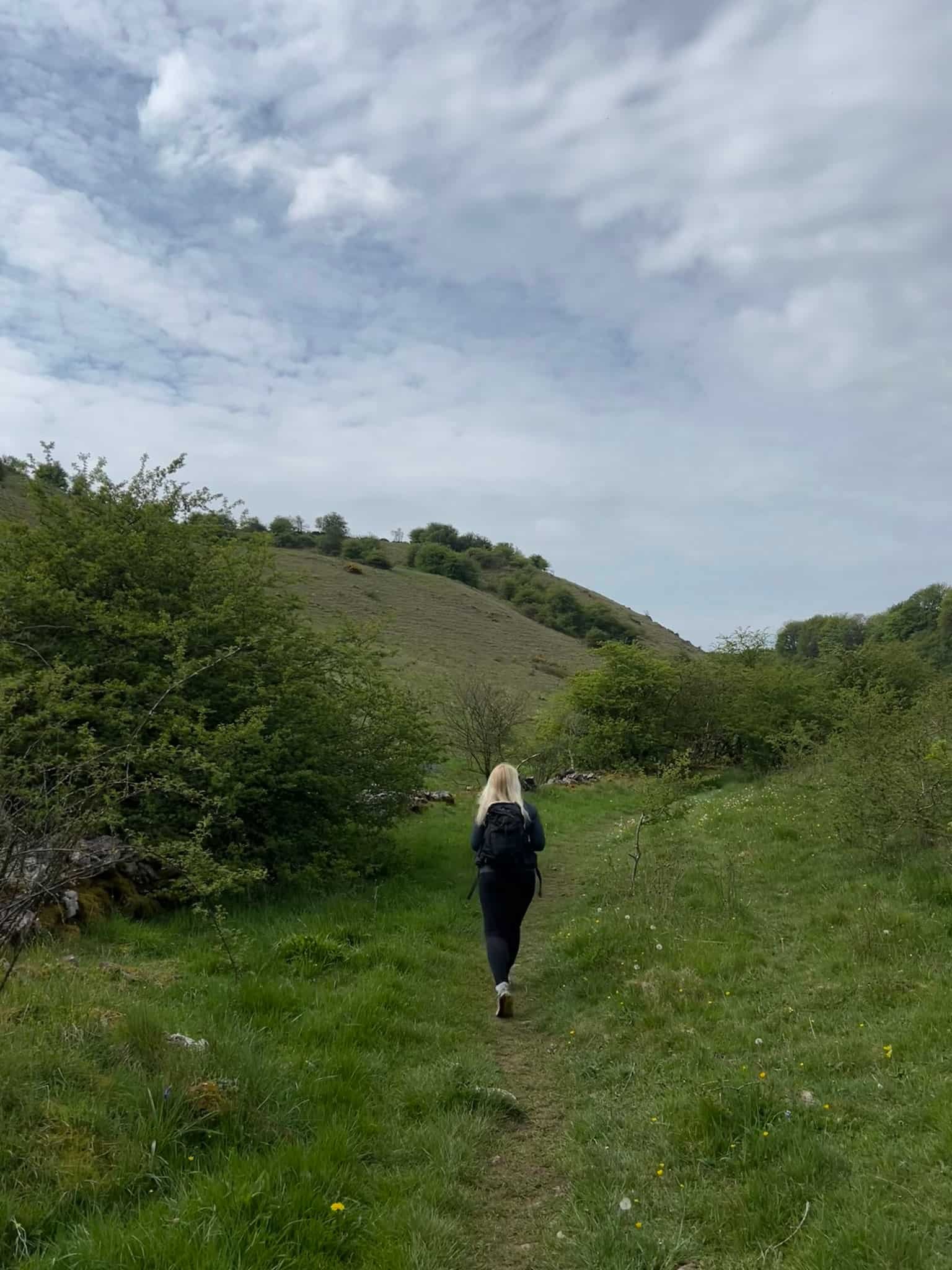 A woman walking in a grassy valley