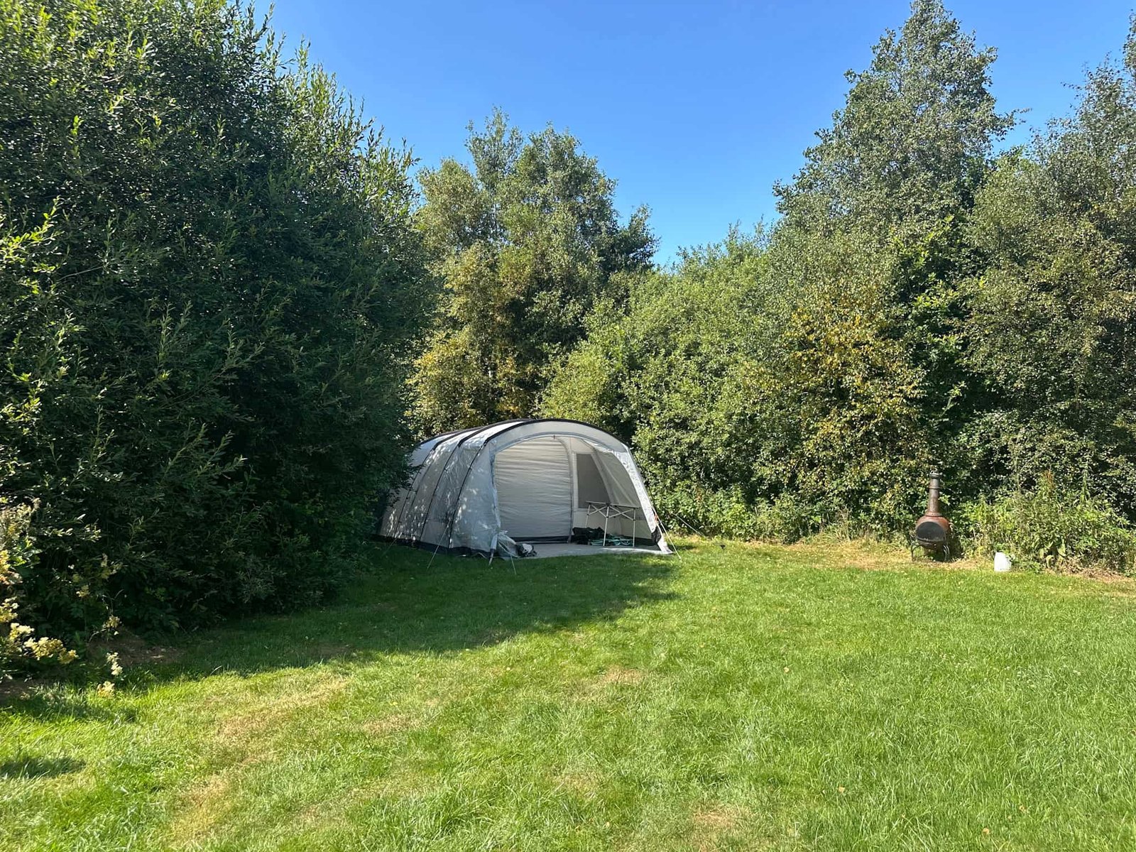 Grey tent in woodland at Toilet block at Cae Ddel Country Camping