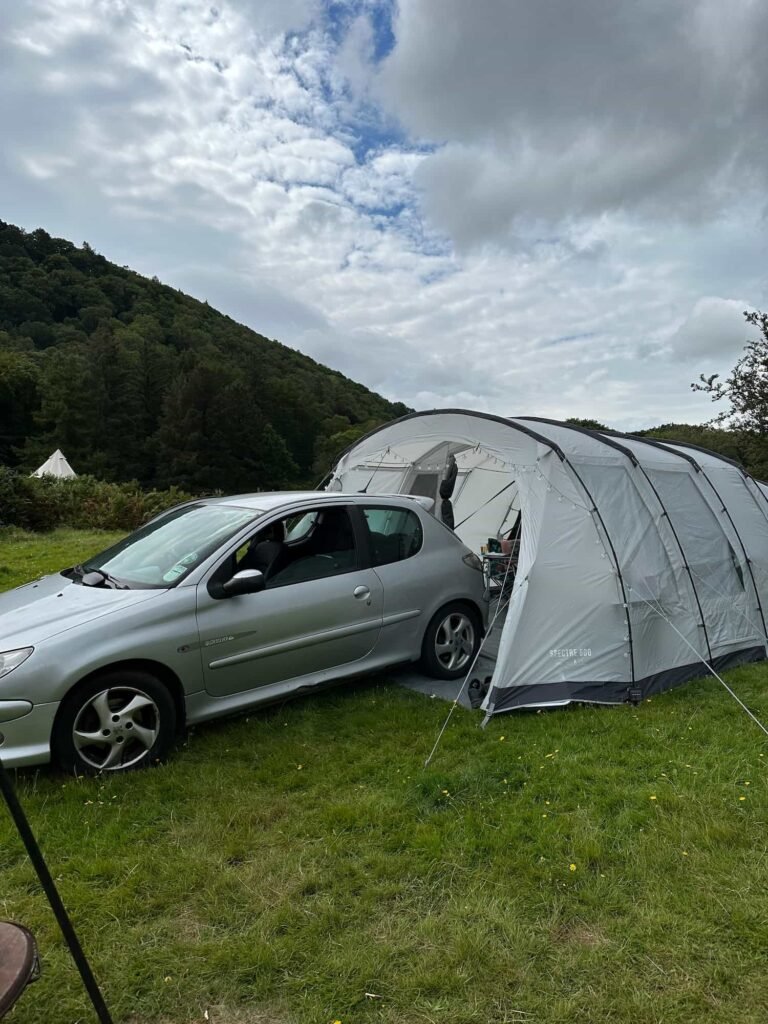 A silver Peugeot 206 being reversed into a grey tent