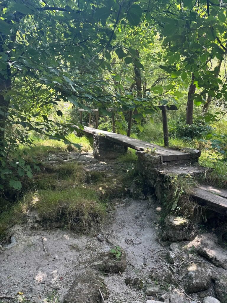 An empty river bed with a wooden bridge over in Monks Dale