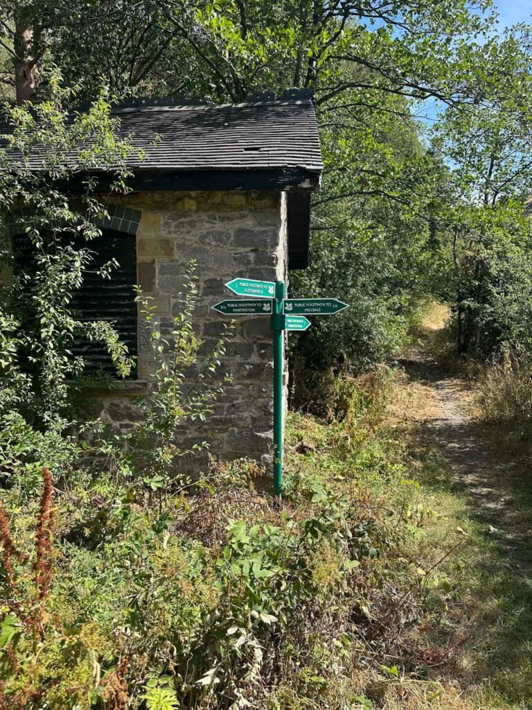 A green signpost with 4 fingers, each with a National Trust logo on.