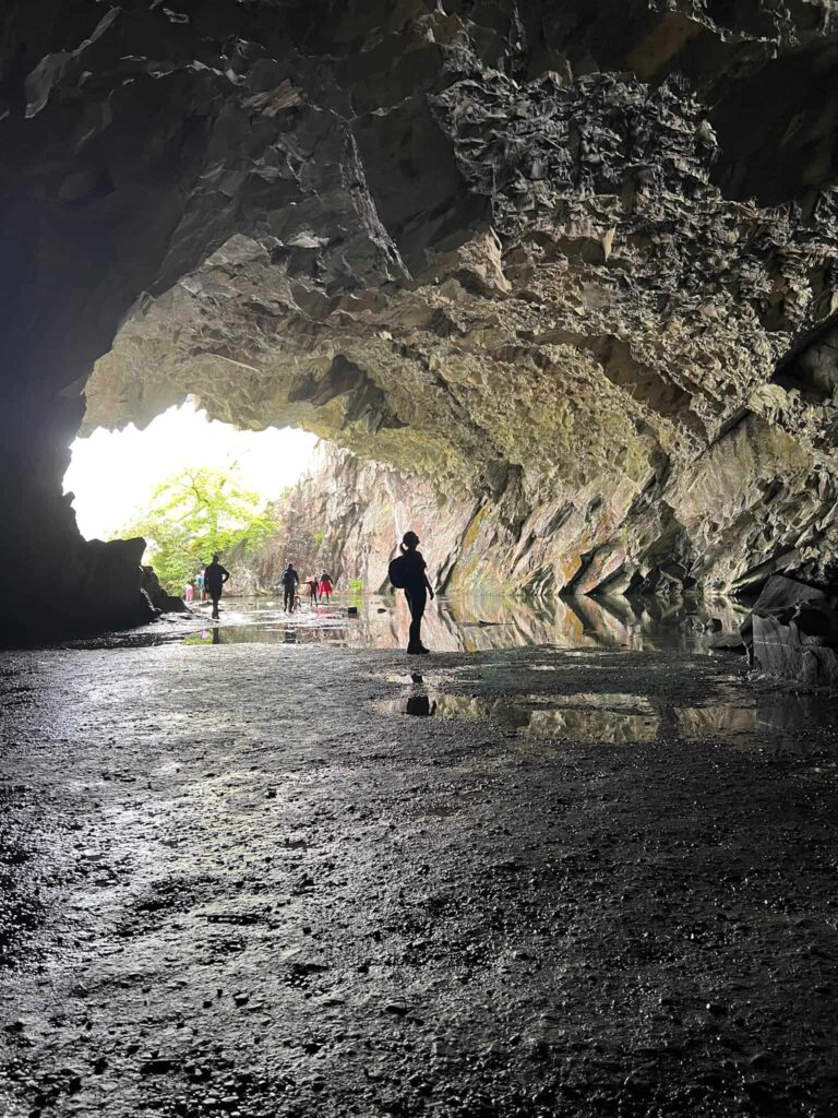 A woman looking at the ceiling in a large cave